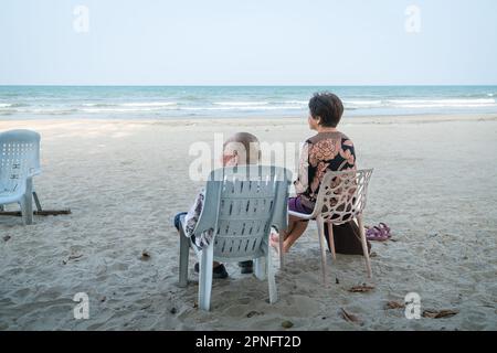 Senior couple relaxing on the beach, watching the sea. Holiday and vacation concept for the elderly and retirees. Stock Photo