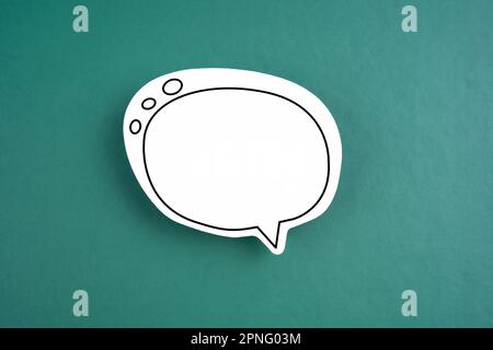 White speech bubble shaped post it note on green background with copy space. Stock Photo