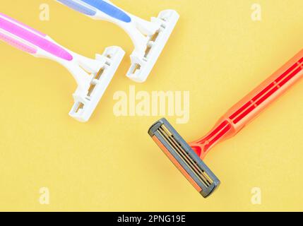 Group of plastic, disposable razors on yellow background. Stock Photo