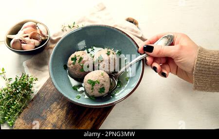 Canederli or Knodel in broth with green onion, typical pasta or dumplings for Alps, Alto Adige, German, Italian, Austrian cuisine. Made from stale bre Stock Photo