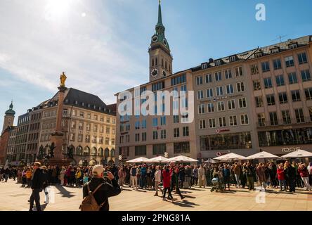 Tourists looking at the carillon on the New Town Hall (not in the picture) at Marienplatz, tower of St. Peter's Church (Alter Peter) in the Stock Photo