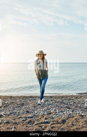 I think I might just stay the night. an attractive young woman enjoying a walk by the lake. Stock Photo