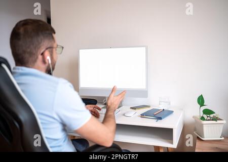 Man working at desk, video calling using his computer. Stock Photo