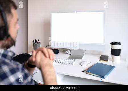 Blank screen computer monitor, man sitting at desk and looking at screen. Stock Photo