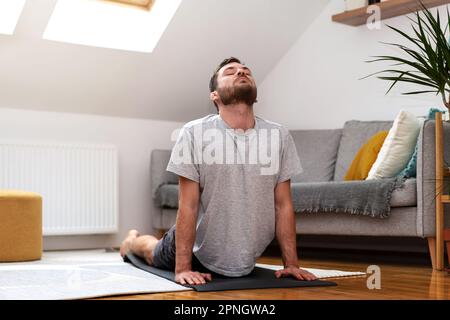 Adult man doing stretching exercise on yoga mat at home. Stock Photo