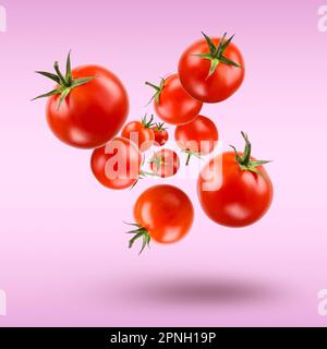 Small red cherry tomatoes floating on violet background. Stock Photo