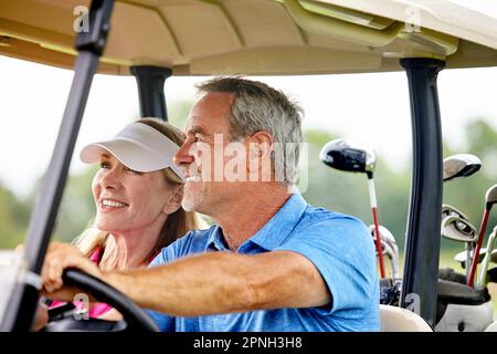 Ready for a game of golf. a couple riding in a golf cart on a golf course. Stock Photo