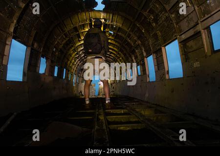 Iceland - August 2021: Artistic shot of a man with lights into  the old crashed plane wreck abandoned in a remoted black sand beach in Iceland Stock Photo