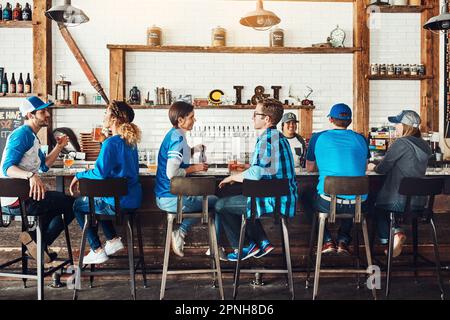 Chilled out at their sports bar of choice. a group of friends having beers while watching a sports game at a bar. Stock Photo