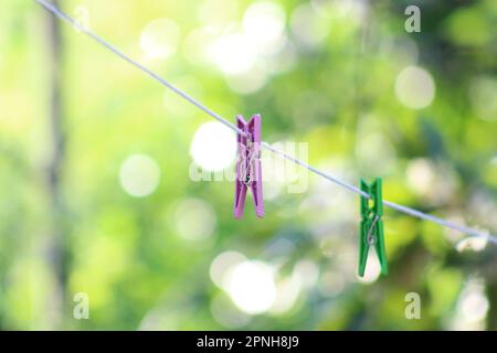 Clothes pegs, selective focus on pink clothes peg on white clothesline. Stock Photo