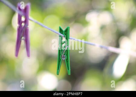 Clothes pegs, selective focus on green clothes peg on white clothesline. Stock Photo