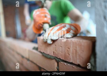 Bricklayer lays bricks on cement building exterior or interior walls Stock Photo