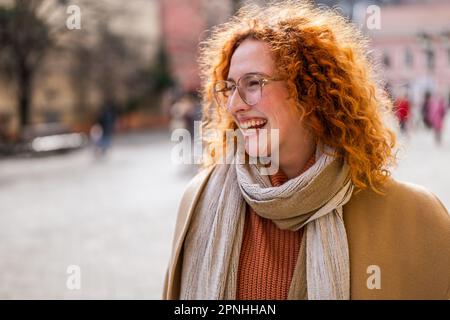 Natural portrait of smiling caucasian ginger woman with freckles and curly hair. Stock Photo