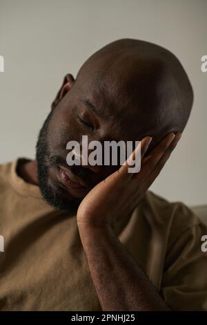 Vertical image of African American depressed man having headache isolated on grey background Stock Photo
