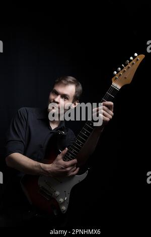 Caucasian man guitarist playing on electric guitar on black background Stock Photo