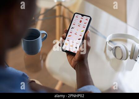 Close up of black man using food delivery and online grocery shopping app via smartphone, copy space Stock Photo