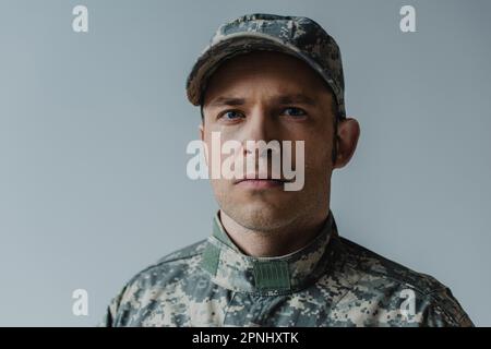 upset soldier in military uniform crying during memorial day isolated on grey Stock Photo