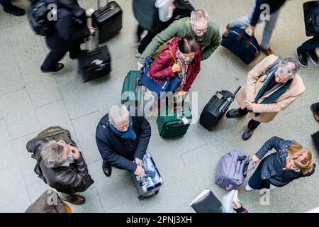Passengers meeting at train station, listening to group leader at train station Stock Photo