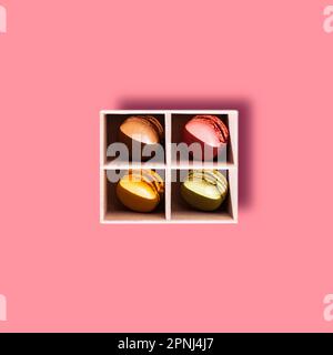 Colourful French macaroon, a sweet meringue-based confection, placed in a box on a colourful background with pieces of fresh berries: strawberries, gr Stock Photo