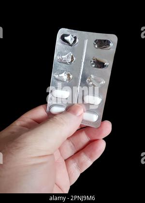 Hand holding pills isolated on black Stock Photo
