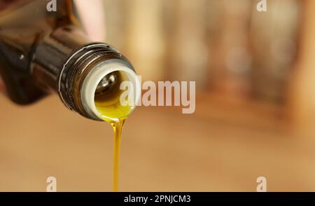 Pouring olive oil from glass bottle. Bottle Neck of Olive Oil Pouring Down a Macro Shot. Stock Photo