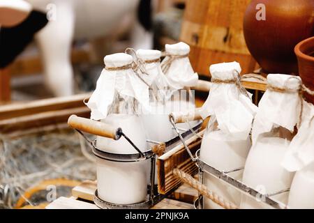 Glass bottles with fresh natural milk, aluminum cans on hay on dairy farm. Healthy farm products Stock Photo