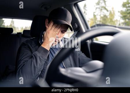 Tired man in car. Sleepy drowsy driver, fatigue. Driving and sleeping in vehicle. Exhausted, bored or drunk person. Serious upset man with stress. Stock Photo