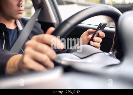 Texting and driving a car. Using mobile phone in traffic. Distracted driver, accident or crash. Irresponsible man typing sms text message. Stock Photo