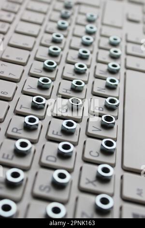 Vertical Stock Photo Of Small Hex Nuts Laid Out In Order On A Keyboard Stock Photo