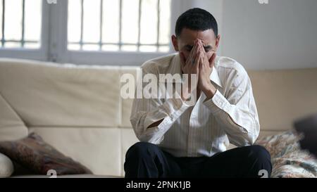 One desperate Arab young man feeling hopeless at home sitting on couch. Person suffering from mental crisis Stock Photo
