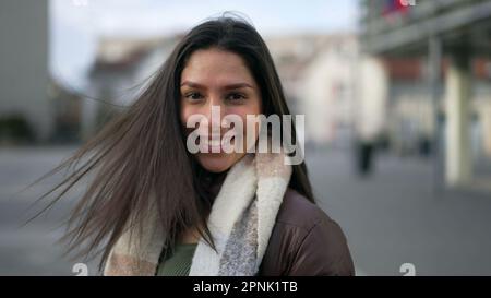 One happy carefree young woman turning head to camera smiling. Portrait face closeup of a female joyful adult girl with long hair and big smile Stock Photo