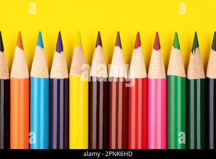Colored pencils on a yellow background. Multi-colored pencils. Stock Photo