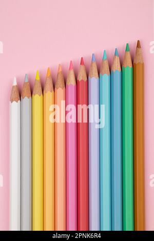 Colored pencils of pastel colors on a pink background. Multi-colored pastel pencils. Stock Photo
