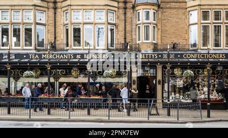 HARROGATE, UK - APRIL 3, 2023.  A line of customers queuing outside the exterior of the Betty's Cafe and Tea Rooms in Harrogate, North Yorkshire Stock Photo