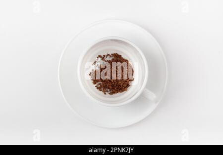 A white cup with instant coffee on a white background. Blank cup. Top view. Stock Photo