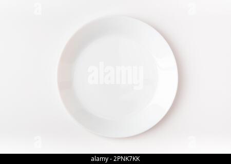 An empty white plate on a white background. Blank plate. Top view. Stock Photo