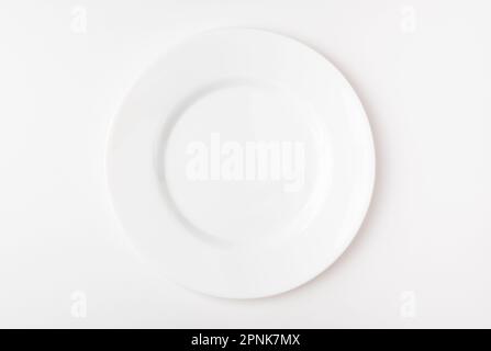 An empty white plate on a white background. Blank plate. Top view. Stock Photo