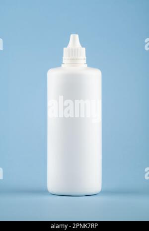 White medical liquid container on light blue background. Plastic blank bottle health care and medical top view on colored blue background. Stock Photo