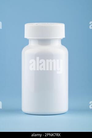 White medical container of pills on light blue background. Drugs and health supplement pills into medicine white bottle health care and medical. Stock Photo