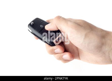 Unlocking a car with button on the keychain. Man's hand holds car key on white background close up. Stock Photo