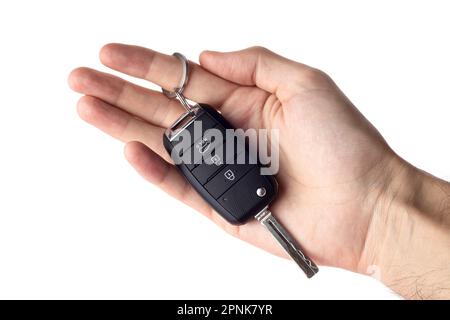 A man's hand holds the car key isolated on a white background close up. Stock Photo