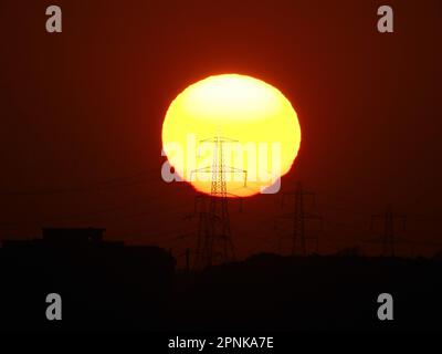 Sheerness, Kent, UK. 19th Apr, 2023. UK Weather: the sun sets behind  electricity pylons in Sheerness, Kent. Credit: James Bell/Alamy Live News Stock Photo