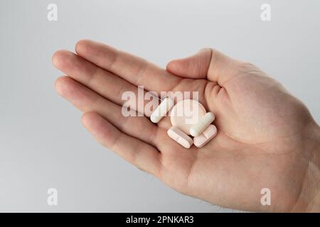 Male hand holding pills in hand on grey background, taking Your medication. Close up Stock Photo