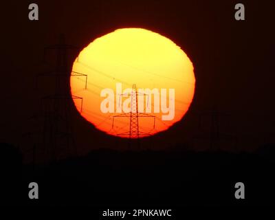 Sheerness, Kent, UK. 19th Apr, 2023. UK Weather: the sun sets behind  electricity pylons in Sheerness, Kent. Credit: James Bell/Alamy Live News Stock Photo