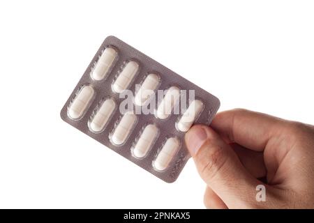 Hand holding a blister of pills on a white background. Stock Photo