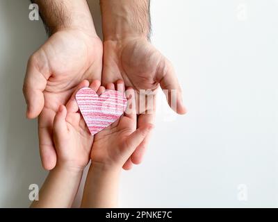 adult and childrens hands hold small red paper heart. Fathers Day. Family, love Stock Photo
