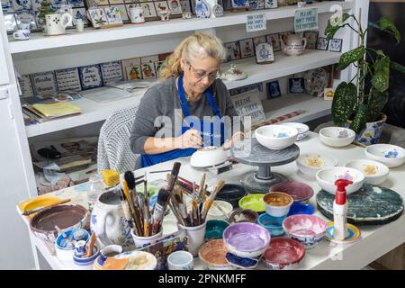 An artisan hand paints traditional Azorean pottery at the Ceramica Vieira on the Azorean Island of Sao Miguel in Lagoa, Portugal. Ceramica Vieira is owned and operated by the same family since 1862 creating Portuguese tiles and artisanal ceramic pieces by hand. Stock Photo