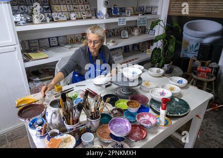 An artisan hand paints traditional Azorean pottery at the Ceramica Vieira on the Azorean Island of Sao Miguel in Lagoa, Portugal. Ceramica Vieira is owned and operated by the same family since 1862 creating Portuguese tiles and artisanal ceramic pieces by hand. Stock Photo