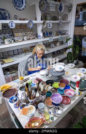 An artisan hand paints traditional Azorean pottery at the Ceramica Vieira on the Azorean Island of Sao Miguel in Lagoa, Portugal. Ceramica Vieira is owned and operated by the same family since 1862 creating Portuguese tiles and artisanal ceramic pieces by hand. Stock Photo