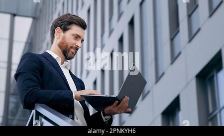 Concentrated caucasian man typing on laptop professional businessman freelancer working remotely using computer application successful pensive male Stock Photo
